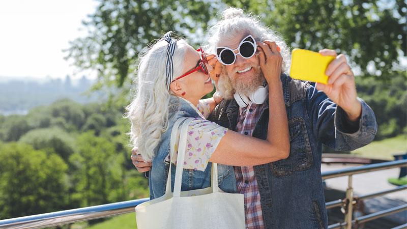 Baby boomer travelers taking a selfie on a smartphone.