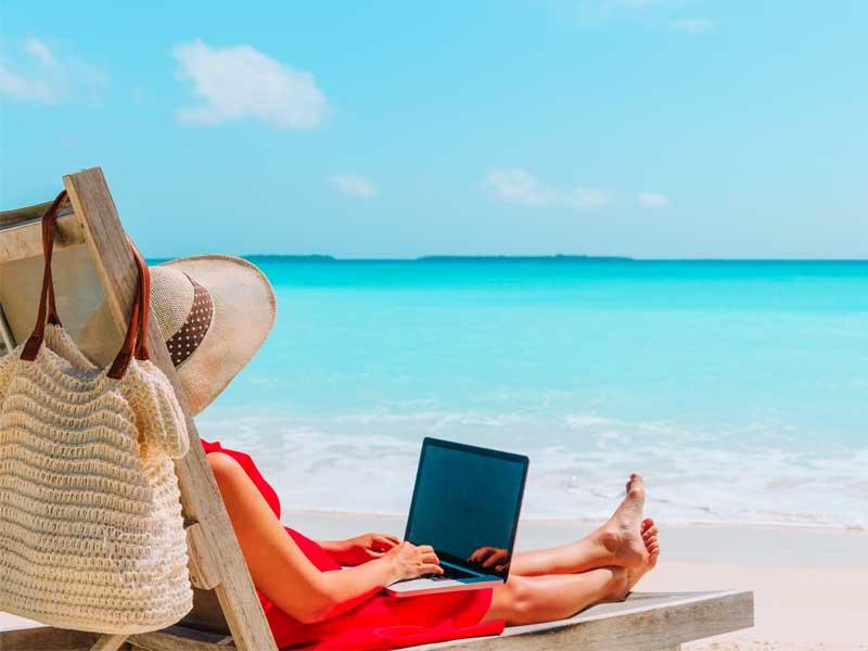 woman sitting on beach with laptop