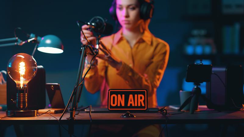 Podcaster in studio with a sign that reads "ON AIR"